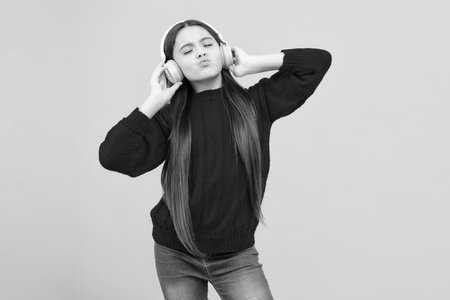 Stylish teenage girl listening to music with headphones. Kids lifestyle concept. Wireless earphones.の写真素材