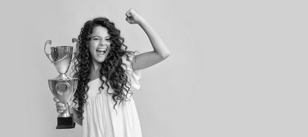 happy teen girl hold golden cup. achievement award. celebrating success and victory. Horizontal poster of isolated child face, banner header, copy space.の写真素材