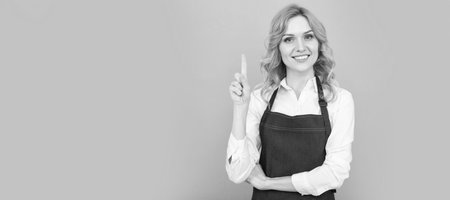 Woman isolated face portrait, banner with mock up copy space. inspired woman in apron pointing finger. housewife express happiness. positive emotions.の写真素材