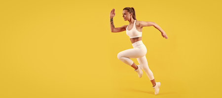 fitness girl runner running in sportswear on yellow background. Woman jumping running banner with mock up copyspace.の写真素材