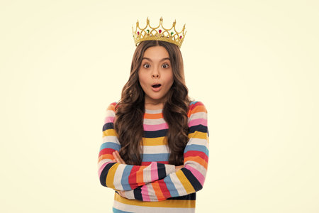 Portrait of ambitious teenage girl with crown, feeling princess, confidence. Child princess crown on isolated studio background. Surprised face, surprise emotions of teenager girl.の写真素材