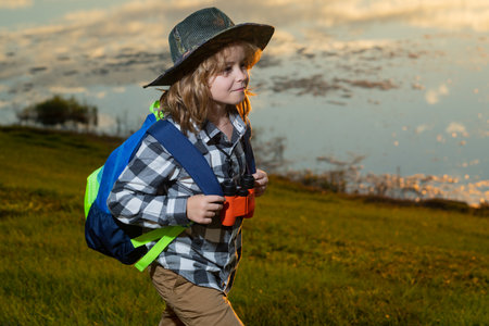 Little child with backpack and binoculars. Imagination or exploration in park. Happy child playing...