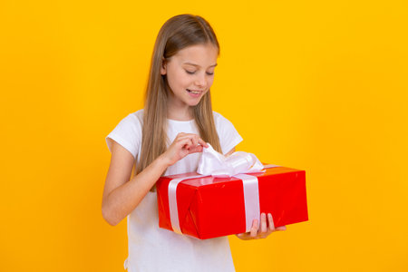 Teen girl hold gift box. Child holding gift box in Christmas or birthday. Girl with giftbox for mothers day. Portrait of a little girl with a gift on isolated background. Birthday, presents gift.の写真素材
