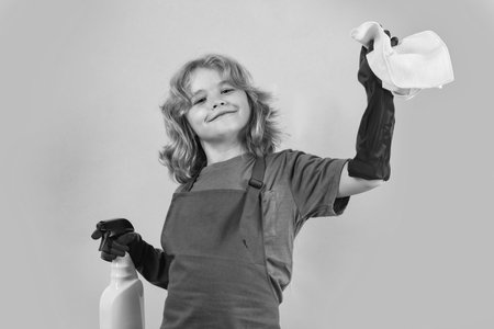 Portrait of child cleaning, concept growth, development, family relationships. Housekeeping and home cleaning concept. Child use duster and gloves for cleaning. Studio isolated background.の写真素材