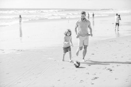 smiling kid and dad running on beach in summer vacation with ball, fathers dayの写真素材