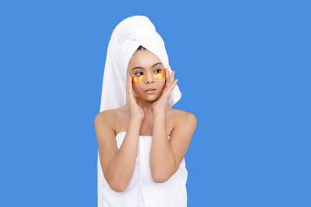 Gold eye patches. Pretty young girl with eye patches, isolated portrait. Teenagers beauty procedures with hydrogel patches on eyes. Skin care of teenagers skin. Moisturizing eyes patches. Beauty teen.の写真素材