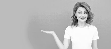 Woman isolated face portrait, banner with copy space. smiling redhead woman with curly hair presenting product looking aside, copy space, advertisement.の写真素材