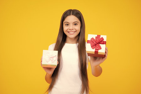 Happy teenager portrait. Child with gift present box on isolated background. Presents for birthday, Valentines day, New Year or Christmas. Smiling girl.の写真素材