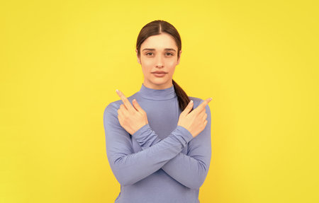 woman portrait pointing fingers on copy space yellow background, gesturingの写真素材