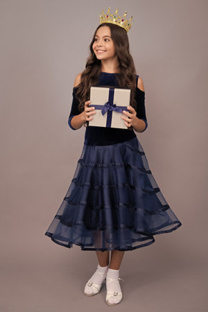 Child with gift present box on isolated studio background. Gifting for kids birthday. Happy face, positive and smiling emotions of teenager girl.の写真素材