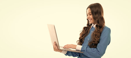 happy child long curly hair typing on laptop isolated on white, school. School girl portrait with...