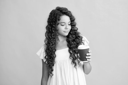 Teen girl holding coffee cup. Coffee break and recess. Teenager hold plastic take away cup, drink cocoa, coffee or tea beverage.の写真素材