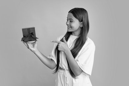 Child teen girl 12-14 years old with gift on isolated background. Birthday, holiday concept. Teenager hold present box. Happy girl face, positive and smiling emotions.の写真素材