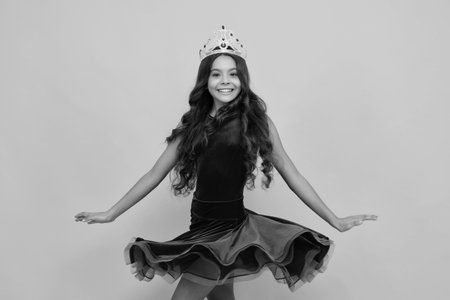 Movement windy dress. Child princess crown on isolated studio background. Happy girl face, positive and smiling emotions.の写真素材