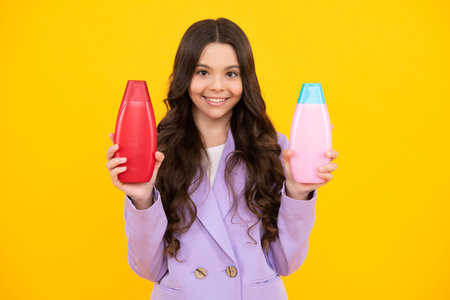 Child teen girl with shampoos conditioners and shower gel. Long hair care of teenager. Presenting cosmetic product, shampoo bottle. Happy teenager, positive and smiling emotions of teen girl.の写真素材
