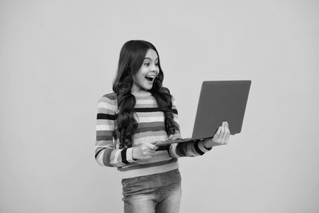 Amazed teenager. School student using laptop. E-learning and online education. Teen girl on internet video chat isolated on isoalted studio background. Excited teen schoolgirl.の写真素材