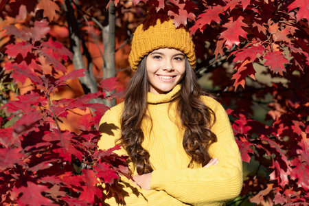 Child teen girl in autumn fall park outdoor, autumn fun kids face. cheerful teen girl in hat at...