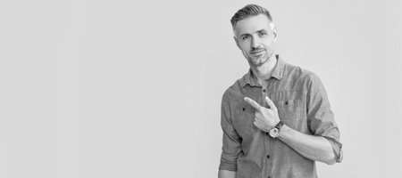 smiling mature man with wrist watch point finger on yellow background, copy space, business hours....