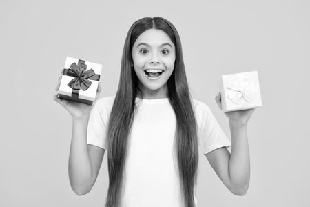 Child with gift present box on isolated background. Presents for birthday, Valentines day, New Year or Christmas. Excited teenager, glad amazed and overjoyed emotions.の写真素材