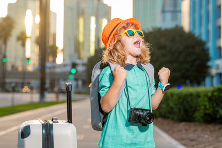 Child traveler with suitcase outdoor. Tourist kid boy having cheerful holiday trip. Child travel with travel bag. Travel and adventure. Child with suitcase dreams of travel, adventure, vacation.の写真素材