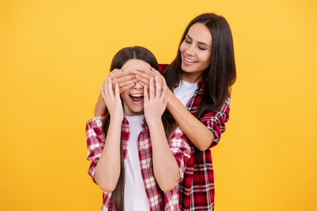 Surprised mother and little daughter. Family happiness. Fun mom with daughter close eyes with hands. Play guess who or hide and seek. Family day. Surprise and family love. Surprise for daughter.の写真素材