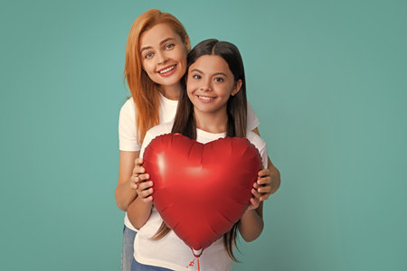 Mothers day. Smiling mother and daughter isolated on blue background. Birthday holiday party, people emotions concept. Celebrating holding heard air balloons.の写真素材