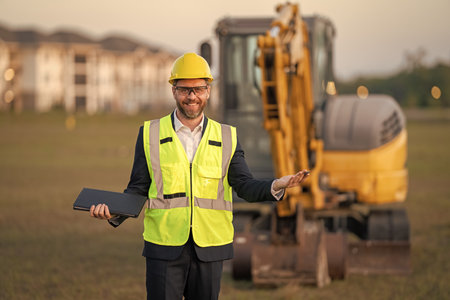 Civil engineer worker at a construction site. Engineer man in front of house background. Confident...