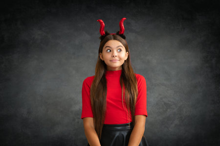 Funny little girl with devil horns. Halloween witch girl. Teen witch. Kid girl witch celebrates...