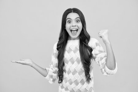 Impressed teenage girl showing recommendation copyspace. Child teenager points away, pointing aside at copy space. Excited face. Amazed expression, cheerful and glad.の写真素材