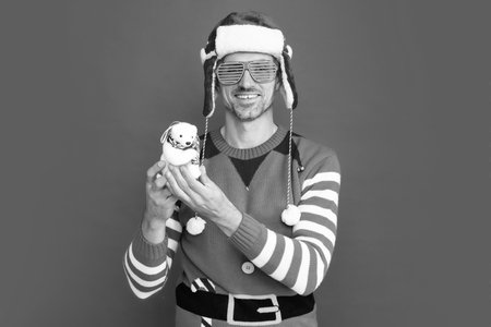 happy man in elf costume and santa claus hat. guy in party glasses hold xmas decorationの写真素材