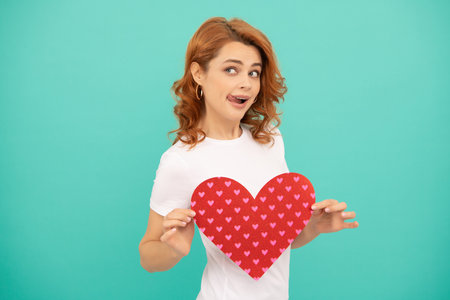 surprised young woman with red heart on blue backgroundの写真素材