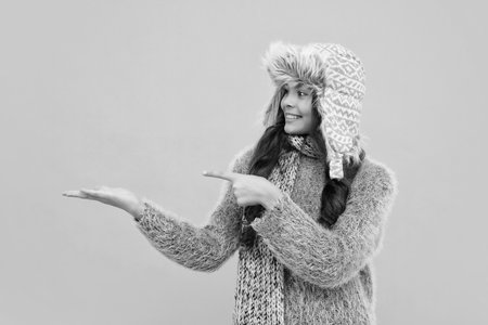 Teenage girl 12, 13, 14 year old wearing sweater and knitted hat on isolated yellow background. Happy face, positive and smiling emotions of girl.の写真素材