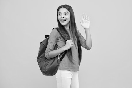 Happy teenager portrait. Schoolgirl in school uniform with backpack. Teenage girl student on yellow isolated background. Learning and education children. Smiling girl.の写真素材