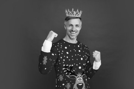 Winter man in crown. Portrait of middle aged man in sweater isolated over red background. Concept of holidays, happiness, emotions and Christmas celebration.の写真素材