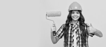 Architect teenager girl. child in helmet. roller brush for decoration. kid education. renovation work. Child builder in helmet horizontal poster design. Banner header, copy space.の写真素材