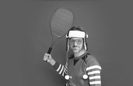 merry christmas. glad man in elf costume and santa claus hat. xmas guy hold tennis rocket