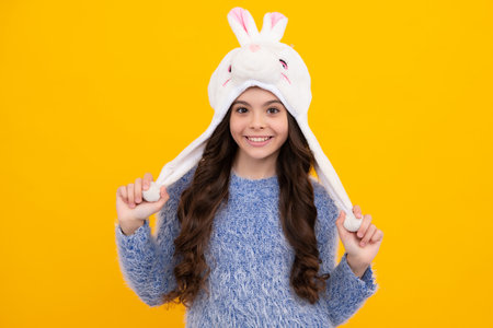 Fun warm hat. Beautiful winter kids portrait. Teenager girl posing with winter sweater and knit hat...