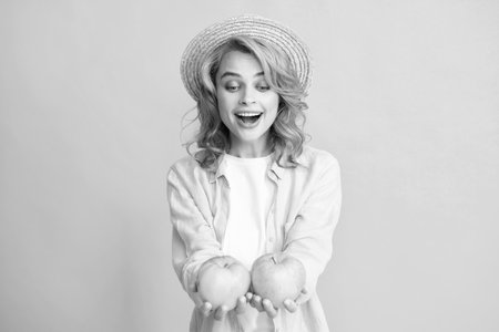 Young woman holding apples smiling with a happy and cool smile on face, showing teeth. Image of happy young pretty woman posing isolated over yellow background holding apple.の写真素材