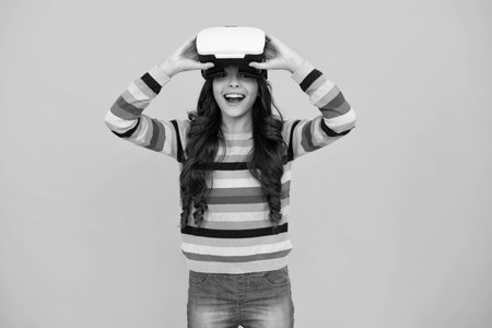 Amazed teenager using VR headset. Kid play vr video game. Digital future and innovation. Child in virtual goggles. Excited teen girl.の写真素材