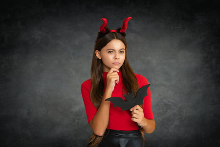 Teen with devil horns hold bat symbol of Halloween Halloween witch teen girl. Little girl witch. Kid witch celebrates Halloween. Portrait of an Halloween child teen girl.の写真素材
