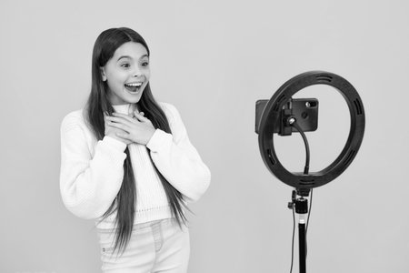 Teenager recording online media video. Teen girl streaming online and sharing social media content by mobile phone app network. Excited face. Amazed expression, cheerful and glad.の写真素材