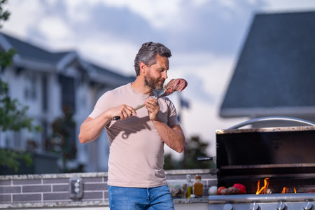 Handsome man preparing barbecue grill outdoor. Man cooking tasty food on barbecue grill at backyard. Chef preparing food on barbecue. Millennial man grilling meat on grill. Bbq party. Meal grilling.の写真素材