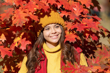 Child girl on autumn fall background, autumn kids face. happy teen child in hat at fall leaves on...