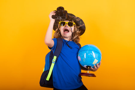 Travel and adventure concept. Little child boy tourist explorer with globe world. Discovery, exploring and education. Studio isolated portrait.の写真素材