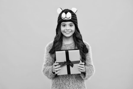 New Year or Christmas holiday gift. Happy teenager, positive and smiling emotions of teen girl. Child with gift present box on isolated studio background. Gifting for kids birthday.の写真素材