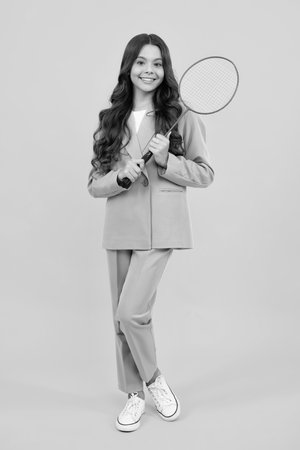 Teen girl badminton player in suit with racket isolated on yellow background.の写真素材