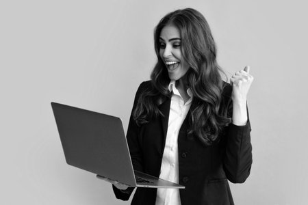 Beautiful smiling business woman over grey background using laptop computer.の写真素材