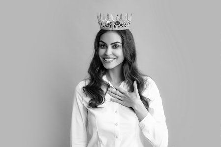 Young lovely woman in crown on gray background. Girl with queen crown celebrating win. Winner concept.の写真素材