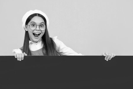 Teenage girl holds a blank for notification informing. Advertisement and sale. Markets and shops sales concept, blank board for copy space. Happy face, positive and smiling emotions of teenager girl.の写真素材