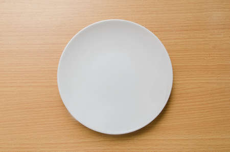 Empty white plate on wooden